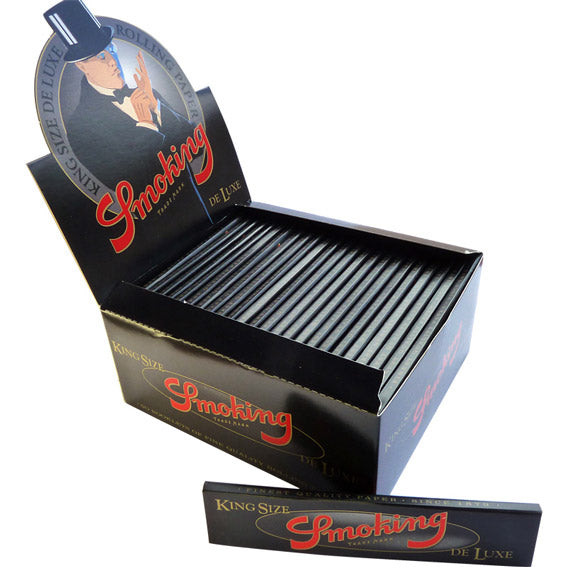 A box of King Size Deluxe Smoking Brand rolling papers with several leaves visible inside the open box.